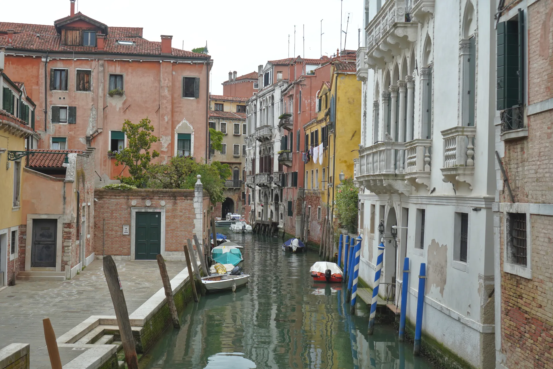 Šarmantni kanal u Veneciji, Italija, sa šarenim zgradama koje se ogledaju u vodi i malim čamcima privezanim uz obalu.